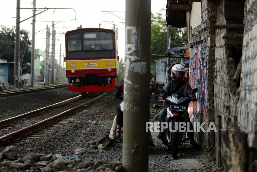 Sejumlah pengendara motor melintasi pinggir rel KRL di kawasan Kedung Badak, Kota Bogor, Jawa Barat, Rabu (19/12).