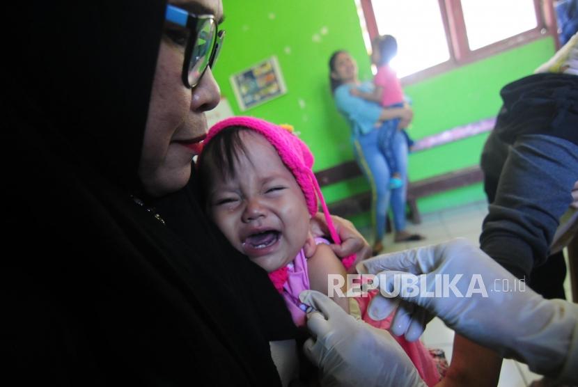 Petugas menyuntikan vaksin pentabio untuk mencegah penyakit difteri kepada anak-anak di Posyandu Desa Cibeber II, Leuwiliang, Kabupaten Bogor, Jawa Barat.