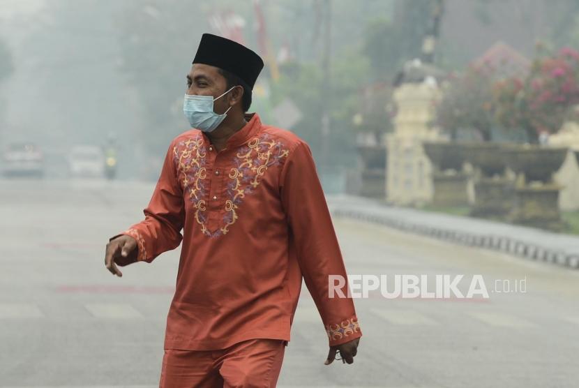 Warga beraktivitas saat asap kebakaran lahan gambut menyelimuti Alun-alun Kabupaten Siak, Riau, Kamis (12/9).