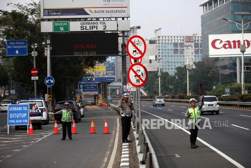 Polisi mengatur lalulintas saat simulasi uji coba penutupan gerbang tol di gerbang Tol Slipi 2, Jakarta, Rabu (1/8).