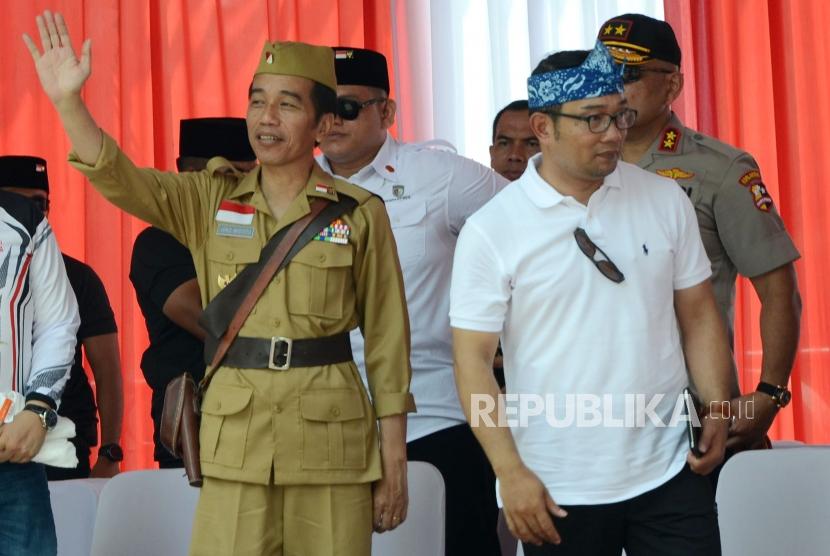 Presiden RI Joko Widodo (Jokowi) menggunakan kostum pejuang didampingi Gubernur Jawa Barat Ridwan Kamil (kedua kanan) melambaikan tangan saat hadir pada acara Bandung Lautan Sepeda dalam rangka Hari Pahlawan, di kawasan Gasibu, Kota Bandung, Sabtu (10/11).