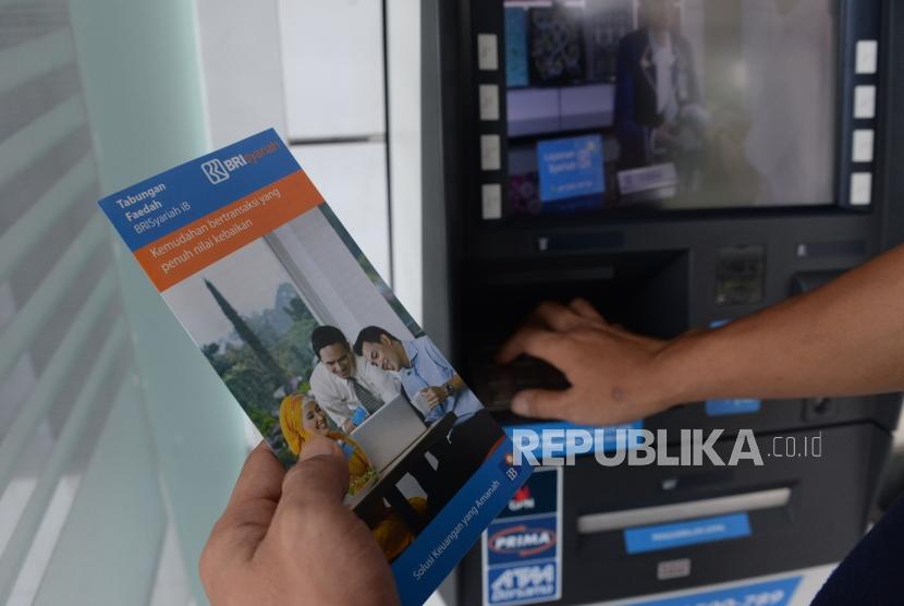 Nasabah membaca brosur usai melakukan transaksi melalui ATM BRI Syariah di Jakarta, Ahad (30/12).