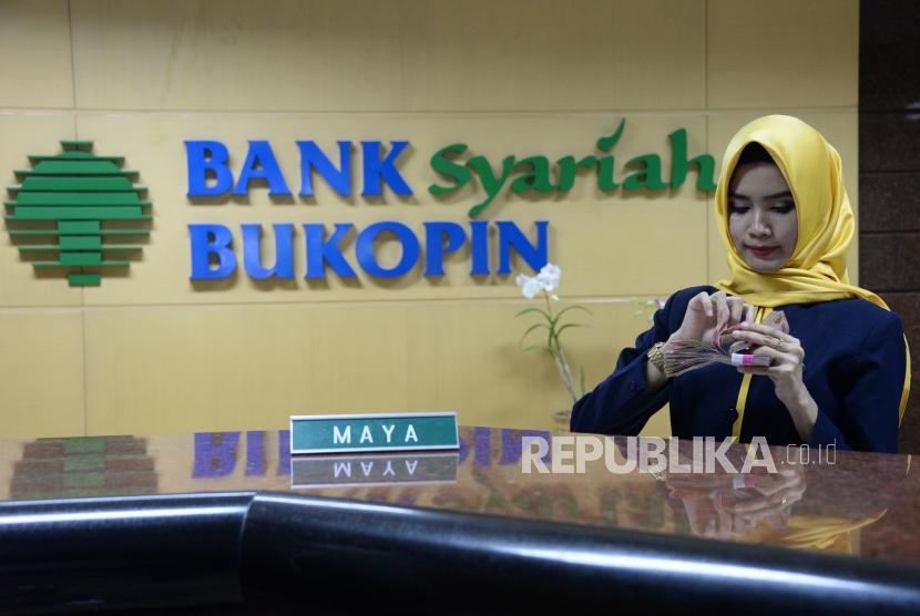 Karyawan melayani nasabah di Bank Syariah Bukopin (BSB), Jakarta,Senin (17/12).