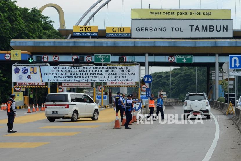 Sejumlah petugas mengatur lalu lintas saat penerapan sistem ganjil-genap di Gerbang Tol Tambun, Bekasi, Jawa Barat, Selasa (4/12).