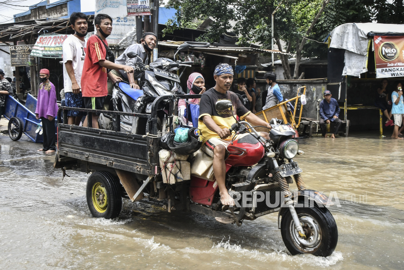 Sejumlah pengendara motor menggunakan jasa gerobak untuk melintasi banjir di Jalan Bosih, Cibitung, Kabupaten Bekasi, Jawa Barat, Senin (8/2/2021). Menurut warga banjir menggenangi wilayah tersebut pada pukul 05.00 WIB akibat luapan aliran kali Jambe. 