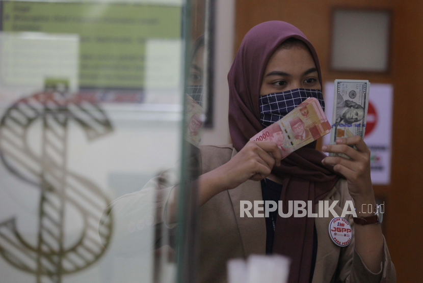Karyawati menunjukkan mata uang rupiah dan dolar AS di salah satu gerai penukaran mata uang asing di Jakarta (ilustrasi). Rupiah pada perdagangan Jumat (3/7) pagi kembali tertekan karena sentimen negatif.