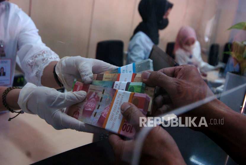 Petugas melakukan transaksi dengan nasabah saat penukaran uang di BNI Kota Tegal, Jawa Tengah, Jumat (15/5/2020). 