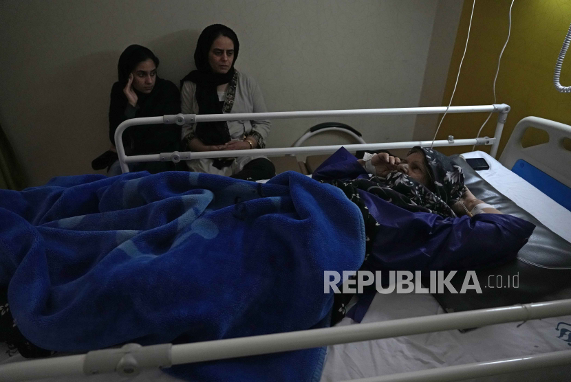 Fatemeh Rostami yang terluka dalam ledakan bom, Rabu, terbaring di tempat tidur, sementara putrinya duduk di sebelahnya di rumah sakit Bahonar, kota Kerman sekitar 820 Km tenggara ibu kota Teheran, Ir