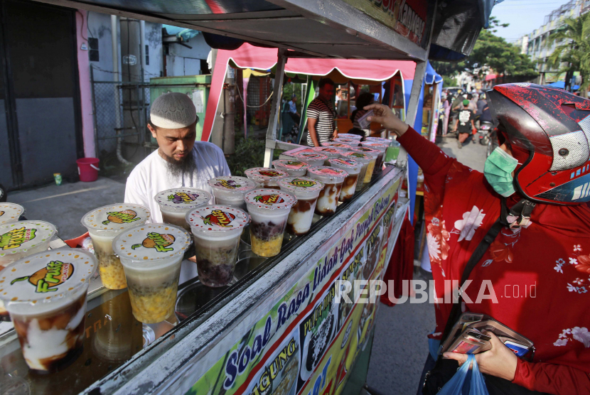 Seorang wanita Muslim membeli buka puasa, makanan yang digunakan umat Muslim untuk mengakhiri puasa Ramadhan harian mereka saat matahari terbenam, di sebuah warung pinggir jalan pada hari pertama Ramadhan di Medan, Sumatera Utara, Indonesia, Selasa, 13 April 2021. 