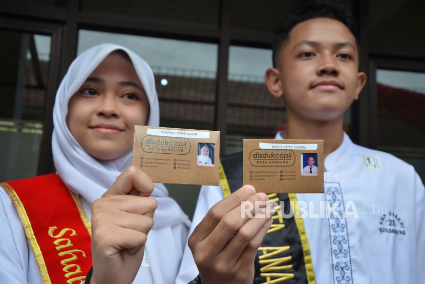 Dua pelajar memperlihatkan kartu identitas anak (KIA) saat acara penyerahan secara simbolis KIA untuk peserta didik di 15 sekolah, yang digelar di SMP Negeri 28 Kota Bandung, Jawa Barat, Jumat (17/2/2023). 