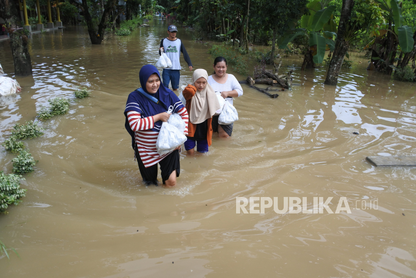 Warga memberikan bantuan nasi bungkus ke korban banjir,  di Desa Wonoasri, Tempurejo, Jember, Jawa Timur, Jumat (15/1/2021). Sebanyak 2.558 KK di desa itu terdampak banjir dengan ketinggian air antara 50 Cm - 2 meter. 