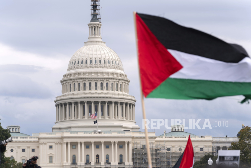 Gedung Capitol AS terlihat di balik bendera Palestina saat orang-orang berunjuk rasa di National Mall selama demonstrasi pro-Palestina di Washington, Jumat, (20/10/2023).