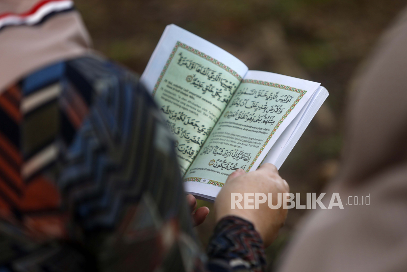 Seorang warga Aceh berdoa dan membaca Kitab Suci Al-Qur