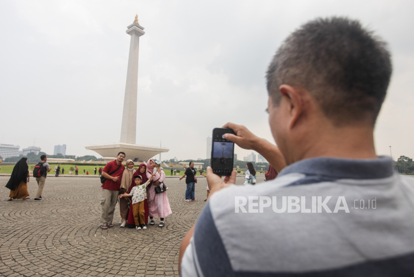 Sejumlah warga berfoto dengan latar belakang Tugu Monumen Nasional (Monas) di Jakarta, Jumat (9/2/2024). 