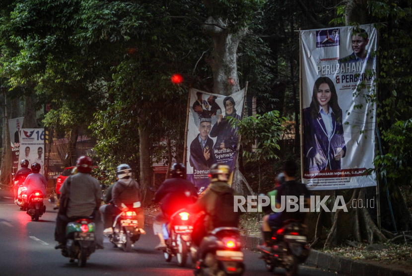 Pengendara roda dua melintas di dekat baliho alat peraga kampanye (APK) di Jalan Ahmad Yani, Kota Bogor, Jawa Barat.