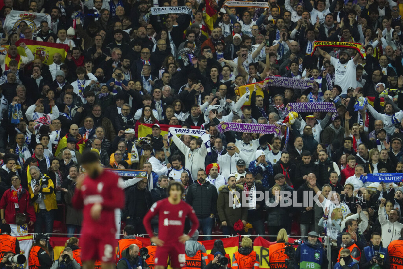 Para pendukung Real Madrid merayakan kemenangan timnya di belakang para pemain Liverpool di Anfield, Rabu (22/2/2023). 