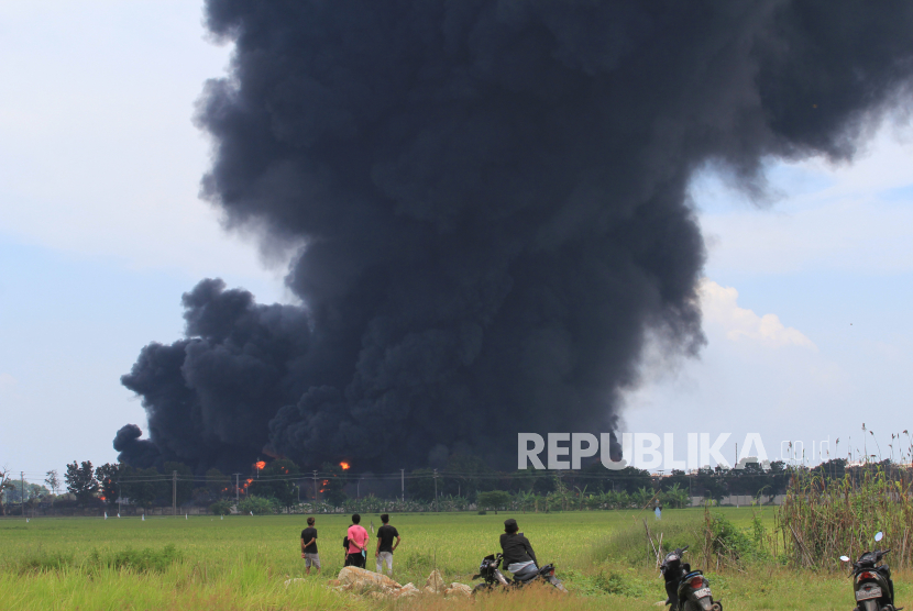 Warga melihat kepulan asap hitam akibat kebakaran tangki minyak milik Pertamina RU VI Balongan, Indramayu, Jawa Barat, Senin (29/3/2021). Akibat kebakaran tersebut sedikitnya 20 orang terluka dan 500 warga yang tinggal di dekat lokasi terpaksa mengungsi. 