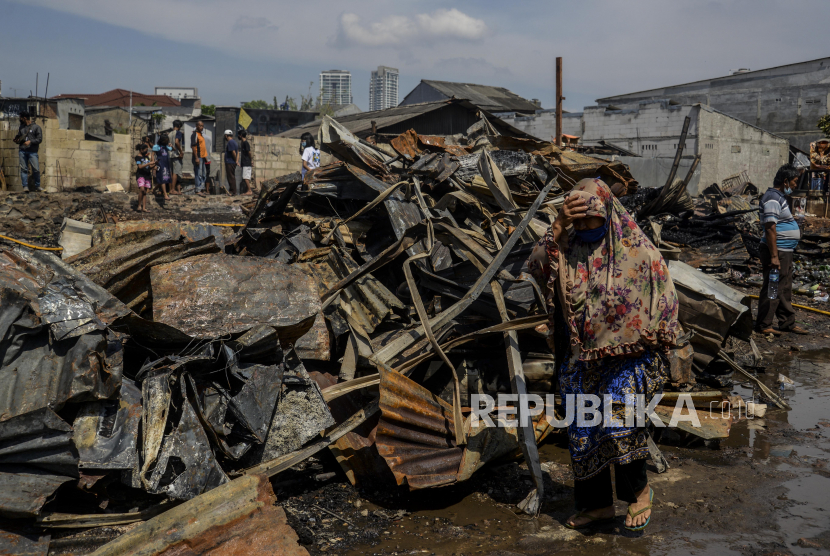 Warga berjalan di dekat puing-puing pasca kebakaran di Jalan Kemang Utara IX, Kelurahan Bangka, Kecamatan Mampang Prapatan, Jakarta Selatan, Ahad (15/8).