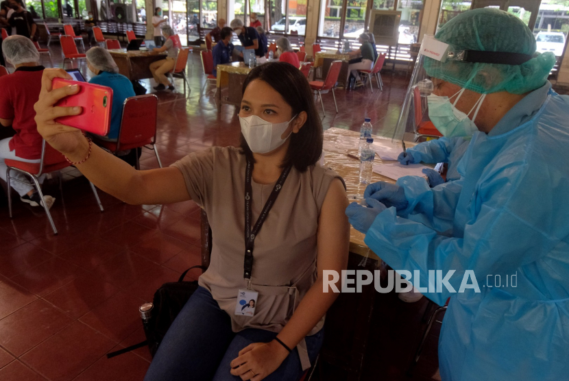 Seorang wartawan melakukan laporan langsung saat disuntikan vaksin COVID-19 (ilustrasi). Ratusan jurnalis dan pekerja media di Sumatra Barat akan mengikuti vaksinasi covid-19 besok, Rabu (10/3) besok.