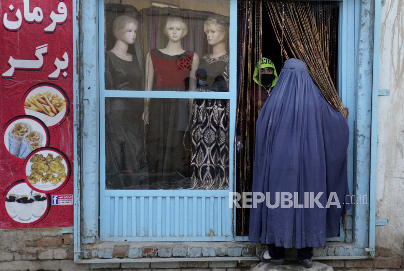 Seorang wanita Afghanistan mengenakan burka memasuki toko penjahit di Kabul, Afghanistan, Selasa, 8 Februari 2022. Taliban Larang Wanita Masuki Taman dan Pasar Malam