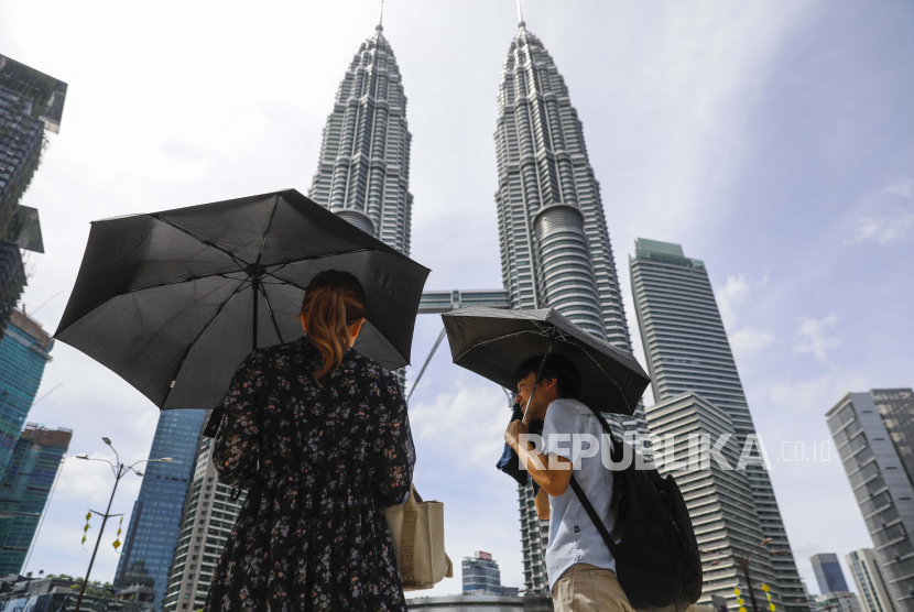 Sepasang suami istri menggunakan payung di siang hari yang panas di Kuala Lumpur, Malaysia (ilustrasi).