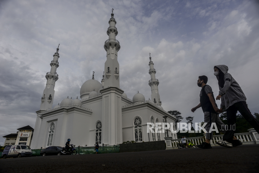 Warga berjalan dengan latar belakang Masjid At-Thohir di kawasan Cimanggis, Depok, Jawa Barat, (ilustrasi).
