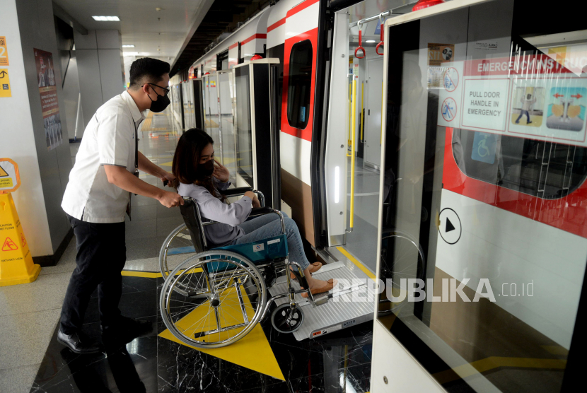 Petugas membatu penumpang dengan menggunakan kursi roda untuk menaiki Rangkaian kereta (Ilustrasi).
