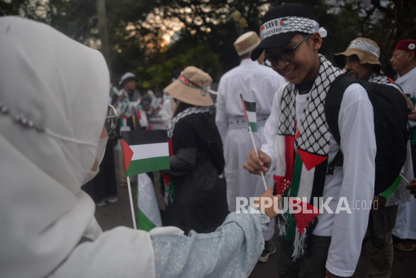 Sejumlah peserta aksi membagikan bendera palestina sebelum dimulainya Aksi DamaiAliansi Rakyat Indonesia Bela Palestina, di kawasan Monas, Jakarta (5/11/2023).