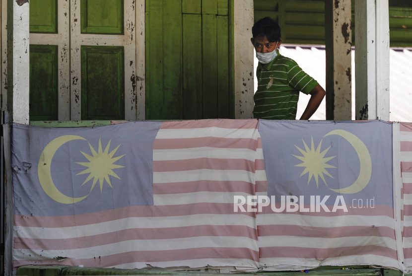 Warga mengenakan masker di rumah mereka di Kampung Baru, sebuah desa tradisional Melayu di pusat kota Kuala Lumpur, Selasa (31/3). Pemerintah Malaysia memerintahkan pembatasan pergerakan terhadap masyarakat hingga 15 April, untuk menghindari penyebaran virus Corona
