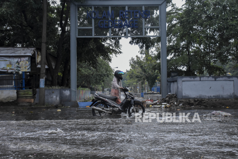 Warga mendorong kendaraannya yang mogok saat melintasi genangan banjir di sekitar pintu masuk Pasar Gedebage, Kota Bandung, Jawa Barat, Jumat (1/12/2023). 
