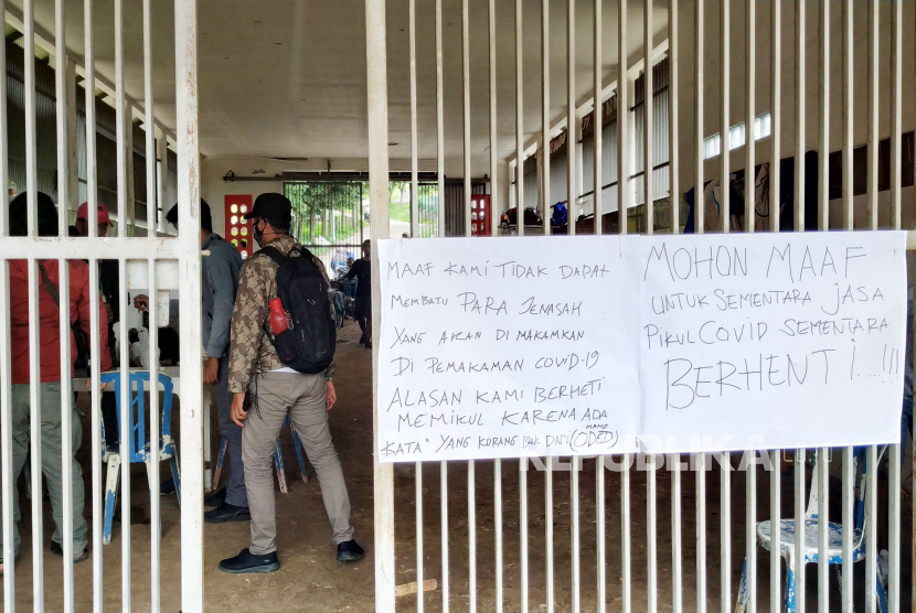 Sebuah poster bertuliskan jasa pikul jenazah Covid-19 berhenti sementara dipasang di gerbang di Pemakaman khusus Covid-19 Tempat Pemakaman Umum (TPU) Cikadut, Kota Bandung, Rabu (27/1). Hal tersebut disebabkan petugas yang biasa mengangkut jenazah positif Covid-19 di TPU Cikadut melakukan aksi mogok bekerja.