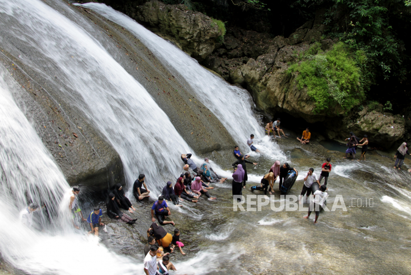 Pengunjung menikmati suasana air terjun di area Taman Wisata Alam (TWA) Bantimurung, Kabupaten Maros, Sulawesi Selatan, Ahad (10/10/2021). 