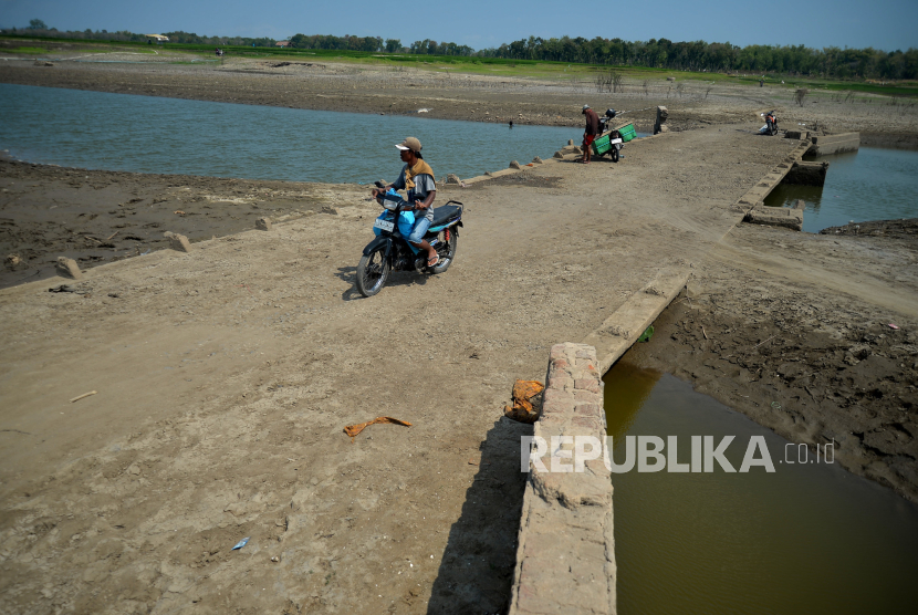 Warga memanfaatkan jembatan lama yang menghubungkan antarkampung muncul kembali imbas kemarau di Waduk Gajah Mungkur, Wonogiri, Jawa Tengah, Jumat (15/9/2023). 