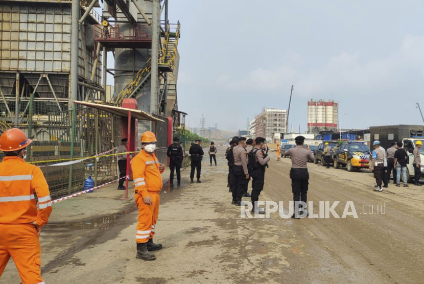 Police officers and workers stand near the site where a furnace explosion occurred at PT Indonesia Tsingshan Stainless Steel smelting plant in Morowali, Central Sulawesi, Indonesia, Sunday, Dec. 24, 2023. A smelting furnace has exploded at the Chinese-owned nickel plant on Indonesia