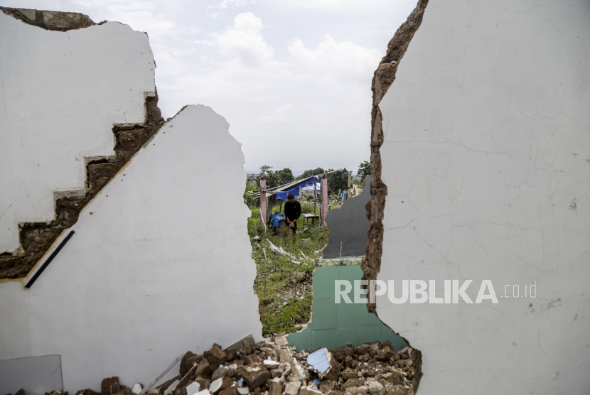 Warga melintas di atas rumah yang hancur akibat gempa (ilustrasi). BNPB sebut gempa pada Jumat dini hari sebabkan 144 rumah rusak di Bogor dan Sukabumi.