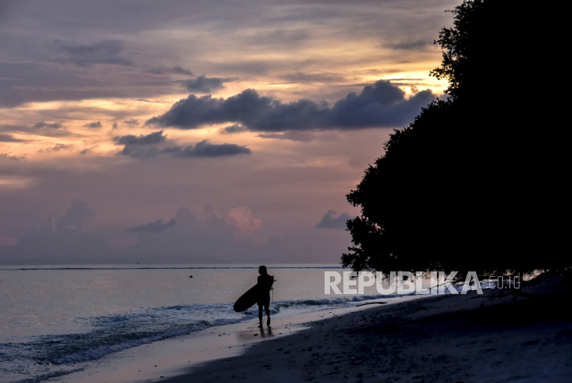 Wisatawan asing membawa papan surfing di pinggiran pantai wisata Gili Trawangan, Kecamatan Pemenang, Tanjung, Lombok Utara, NTB.