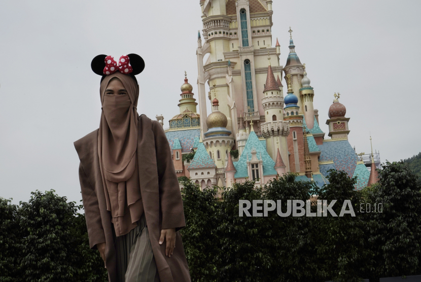 Pengunjung dengan menggunakan masker berfoto di Hong Kong Disneyland, Jumat (25/9). Ilustrasi.