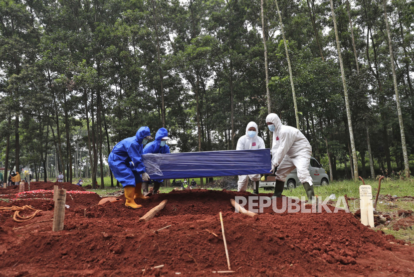 Pekerja berbaju pelindung bersiap menurunkan peti mati berisi jenazah korban COVID-19 ke dalam kuburan di pemakaman Cipenjo di Bogor, Jawa Barat. Hari ini, Rabu (21/7), angka kematian akibat Covid-19 kembali mencatatkan rekor. 