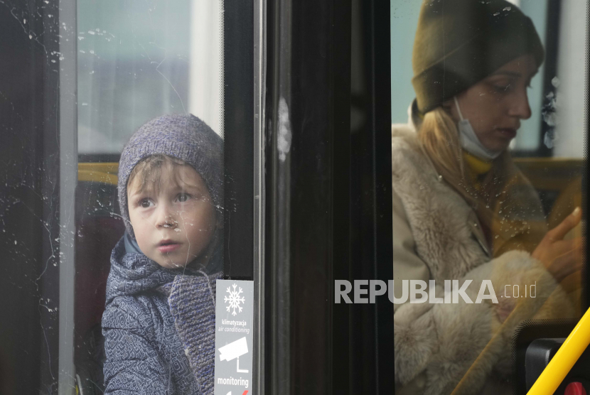  Seorang anak pengungsi melihat keluar dari bus setelah melarikan diri dari perang dari negara tetangga Ukraina di stasiun kereta api pusat di Warsawa, Polandia, Ahad, 27 Maret 2022. 