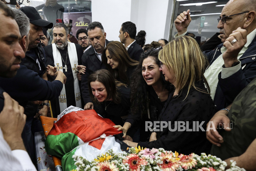 Rekan-rekan dan teman-teman bereaksi ketika tubuh wartawan veteran Al-Jazeera Shireen Abu Akleh yang terbungkus bendera Palestina dibawa ke kantor saluran berita di kota Ramallah, Tepi Barat, Rabu, 11 Mei 2022. 
