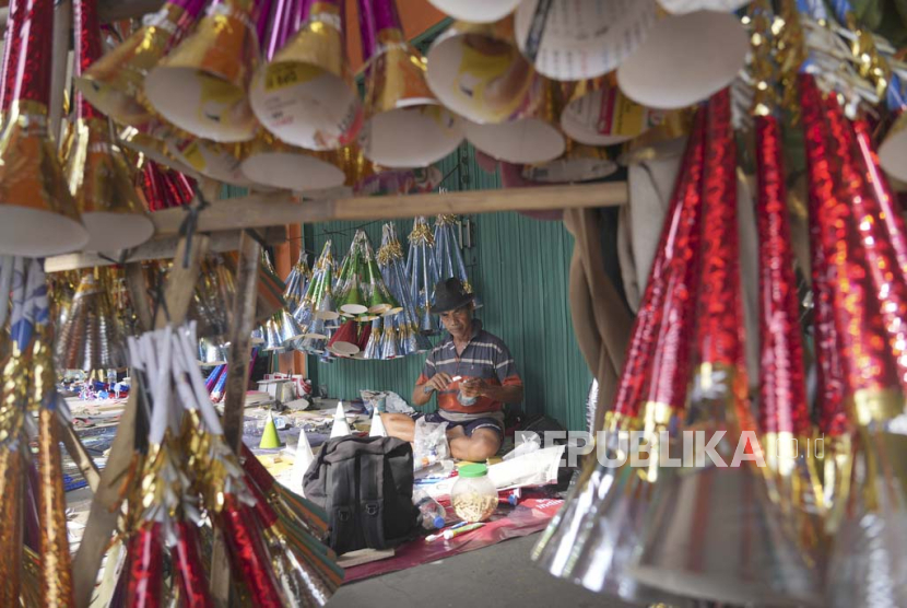 Seorang pedagang membuat terompet dari kertas untuk dijual sebagai persiapan perayaan malam tahun baru di warung pinggir jalan raya Jakarta, Indonesia, Jumat, 29 Desember 2023.
