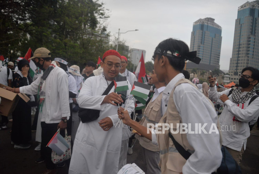 Sejumlah peserta aksi membagikan bendera palestina sebelum dimulainya Aksi DamaiAliansi Rakyat Indonesia Bela Palestina, di kawasan Monas, Jakarta (5/11/2023).