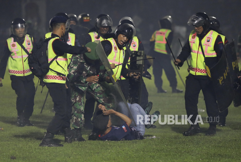 Security officers detain a fan during a clash between supporters of two Indonesian soccer teams at Kanjuruhan Stadium in Malang, East Java, Indonesia, Saturday, Oct. 1, 2022. Panic following police actions left over 100 dead, mostly trampled to death, police said Sunday. (AP Photo/Yudha Prabowo)