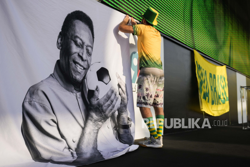  Seorang penggemar memperlihatkan tanda mendukung Pelé di pesta penggemar Brasil sebelum pertandingan sepak bola babak 16 besar Piala Dunia antara Brasil dan Korea Selatan, di Doha, 5 Desember 2022. Pelé yang berusia 82 tahun tetap berada di rumah sakit di San Paulo pulih dari infeksi pernapasan yang diperparah oleh COVID-19, tetapi berita yang datang dari Brasil Senin pagi bagus.