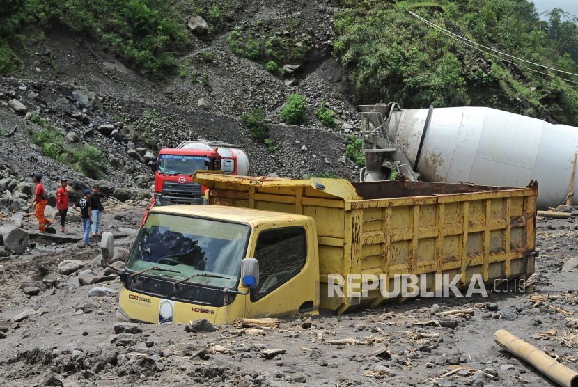 Warga menyaksikan truk yang terjebak lahar hujan di aliran sungai Senowo kawasan lereng Gunung Merapi Dusun Trono, Krinjing, Dukun, Magelang, Jateng, Kamis (2/12/2021). Hujan lebat pada Rabu (1/12/2021) mengakibatkan banjir lahar hujan di sejumlah sungai yang berhulu di Gunung Merapi yang menyebabkan empat truk terjebak dan sejumlah fasilitas proyek pembangunan Sabo Dam rusak. 