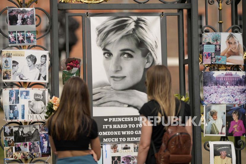 Dua wanita melihat potret Putri Diana dan kenangan lainnya yang dipajang di gerbang Istana Kensington, di London, Selasa, 30 Agustus 2022. Minggu ini menandai peringatan 25 tahun kematian Putri Diana dalam kecelakaan mobil di Paris.