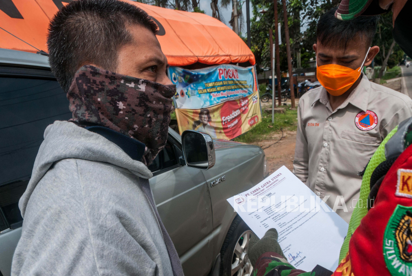 Petugas memeriksa kelengkapan surat keterangan bebas COVID-19 dan surat tugas kepada pengendara dari zona merah saat penyekatan di perbatasan posko Citeras, Lebak, Banten, Senin (18/5/2020). Penyekatan tersebut ditujukan terhadap kendaraan dari zona merah yang tidak membawa kelengkapan surat pernyataan bebas COVID-19 dan surat tugas serta sejumlah pengendara yang nekat mudik guna mencegah penyebaran COVID-19