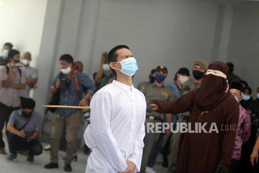  Seorang pria Aceh bereaksi saat ia dicambuk di depan publik karena melanggar hukum syariah, di Banda Aceh, Aceh.