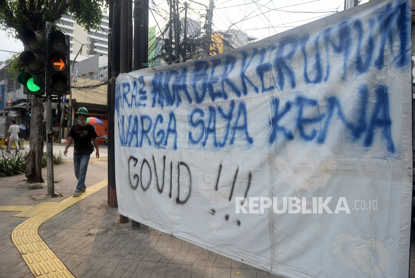 Warga melintas di dekat spanduk peringatan untuk warga yang berkerumun di kawasan Sabang, Jakarta. Puncak kasus Covid-19 usai libur Lebaran diprediksi terjadi pada Juni 2021.