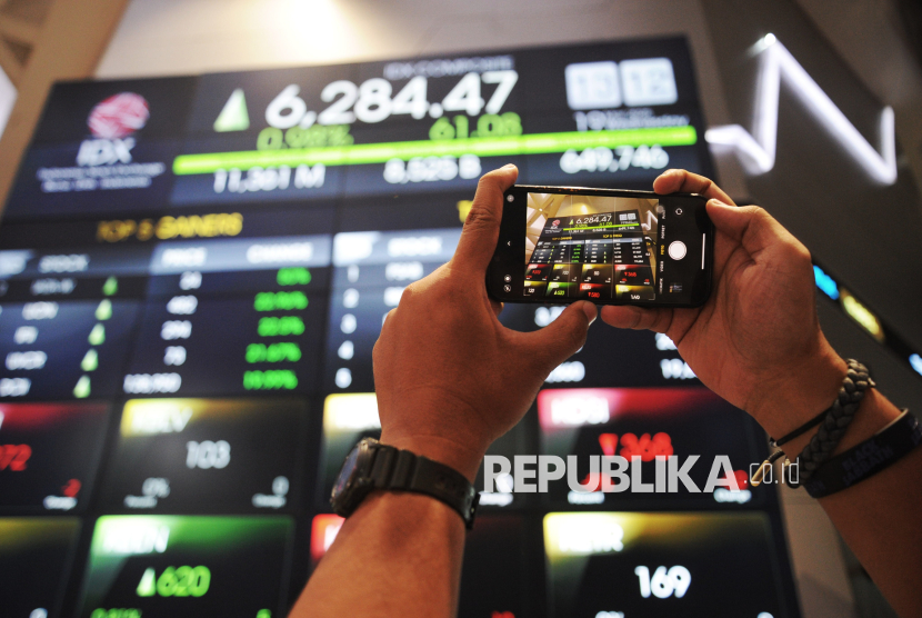 Karyawan memfoto layar eletronik pergerakan perdagangan saham di Bursa Efek Indonesia (BEI), Jakarta, Rabu (19/3/2024). 